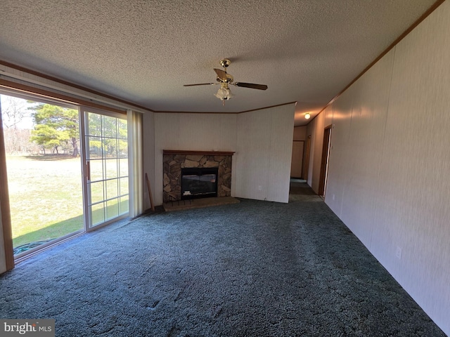 unfurnished living room with carpet floors, ceiling fan, a textured ceiling, and a stone fireplace