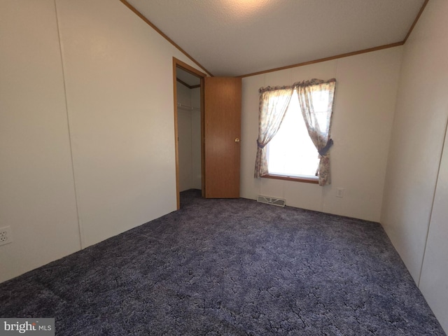 unfurnished bedroom with ornamental molding, carpet flooring, vaulted ceiling, and visible vents