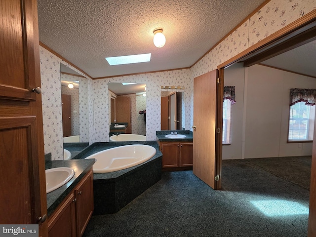 full bath with two vanities, a sink, a textured ceiling, and wallpapered walls