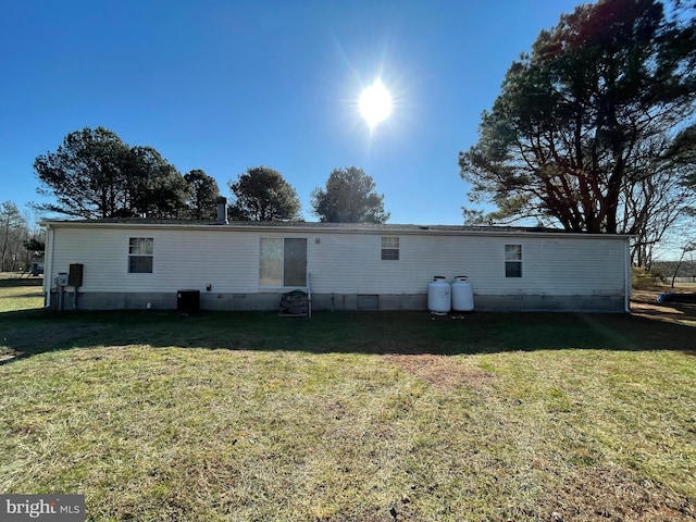 rear view of house with central AC and a yard