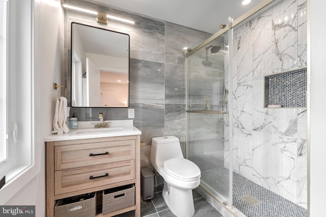 bathroom featuring tile walls, vanity, a shower with shower door, tile patterned floors, and toilet