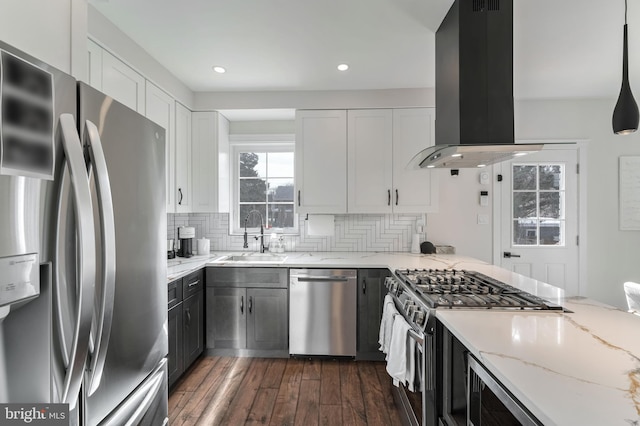 kitchen with sink, white cabinetry, light stone counters, appliances with stainless steel finishes, and island exhaust hood