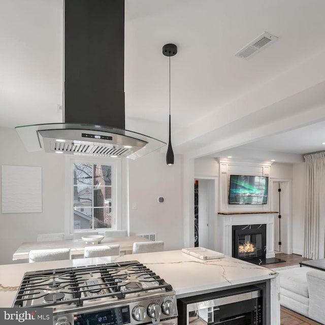 kitchen with pendant lighting, beverage cooler, island exhaust hood, a high end fireplace, and gas range