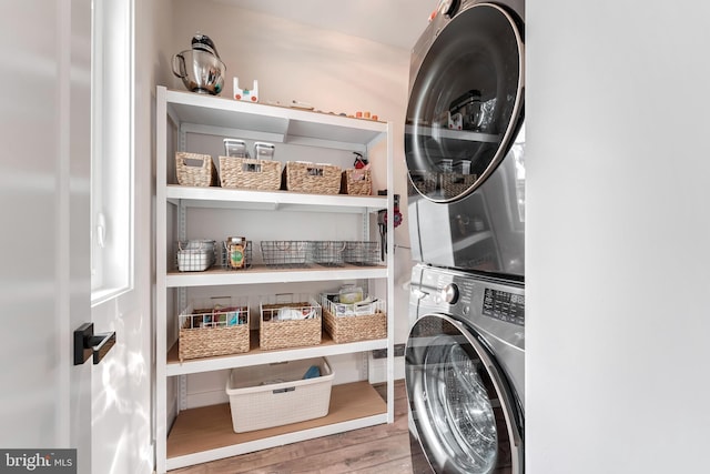 clothes washing area featuring stacked washer / drying machine and hardwood / wood-style floors