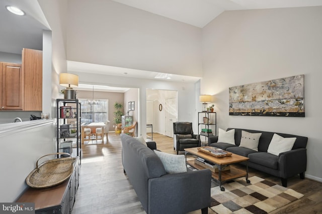 living room with light hardwood / wood-style flooring, high vaulted ceiling, and a chandelier