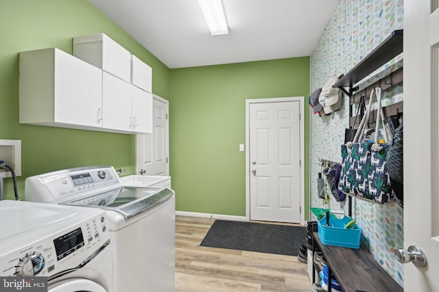 laundry room with cabinets, independent washer and dryer, sink, and light hardwood / wood-style flooring