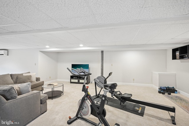 workout area with a paneled ceiling, carpet flooring, and an AC wall unit