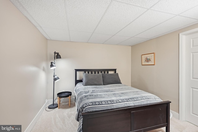 bedroom with light carpet and a paneled ceiling