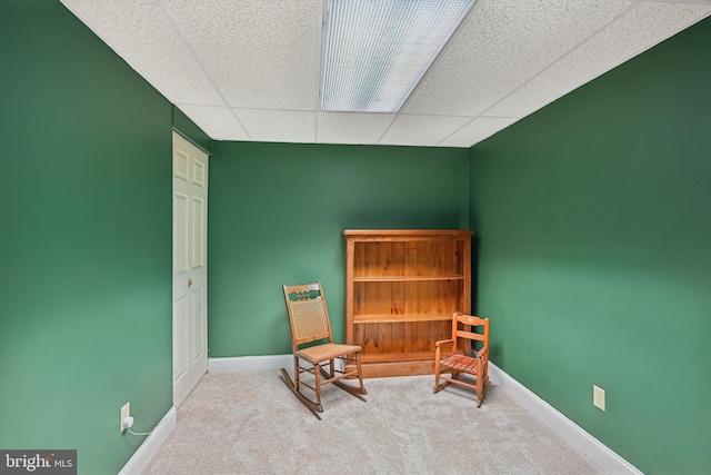 living area with a paneled ceiling and light carpet