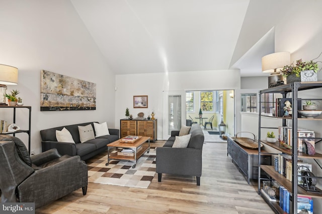 living room with high vaulted ceiling and light wood-type flooring