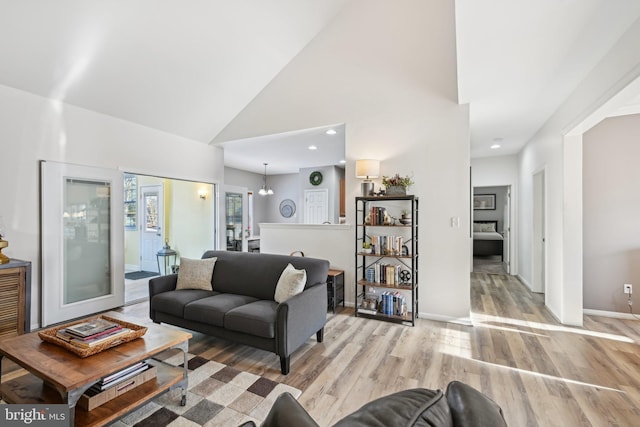 living room with a chandelier, light hardwood / wood-style floors, and high vaulted ceiling