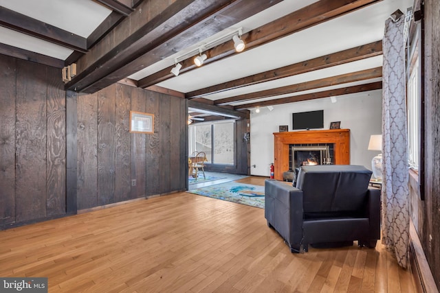 living room with beamed ceiling, light hardwood / wood-style flooring, and wood walls