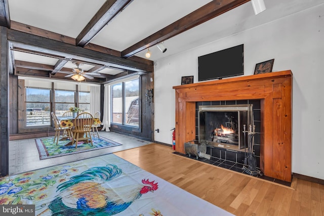 living room featuring hardwood / wood-style floors, beam ceiling, a fireplace, and ceiling fan