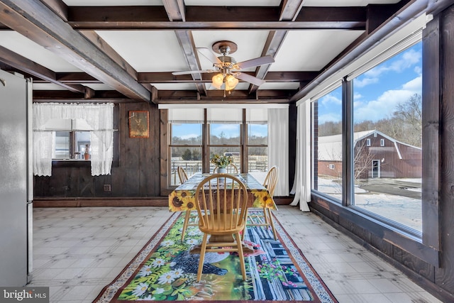 unfurnished dining area featuring beamed ceiling, coffered ceiling, wooden walls, and ceiling fan