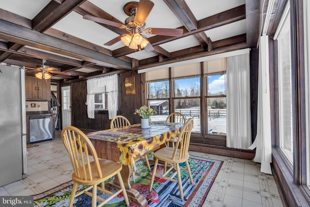 dining area featuring coffered ceiling, beam ceiling, ceiling fan, and wood walls