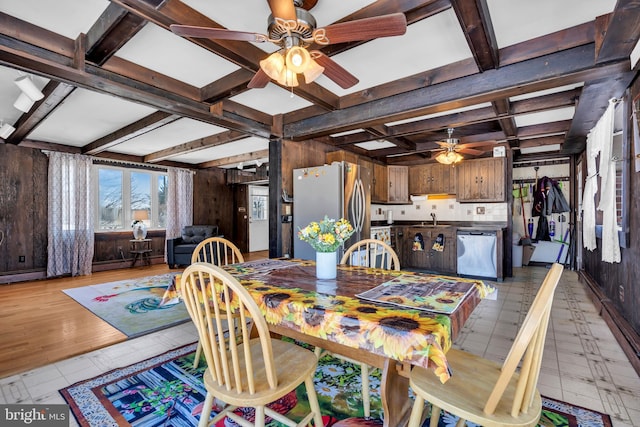 dining area featuring beam ceiling, ceiling fan, sink, and wooden walls