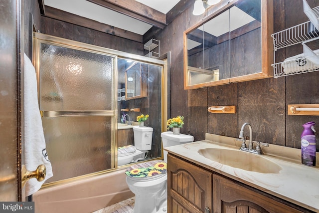 full bathroom with combined bath / shower with glass door, wooden walls, beamed ceiling, vanity, and toilet