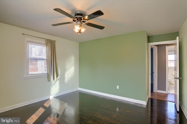 spare room with dark wood-type flooring, ceiling fan, and plenty of natural light