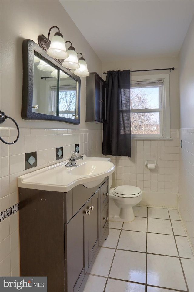 bathroom with tile patterned floors, toilet, and tile walls