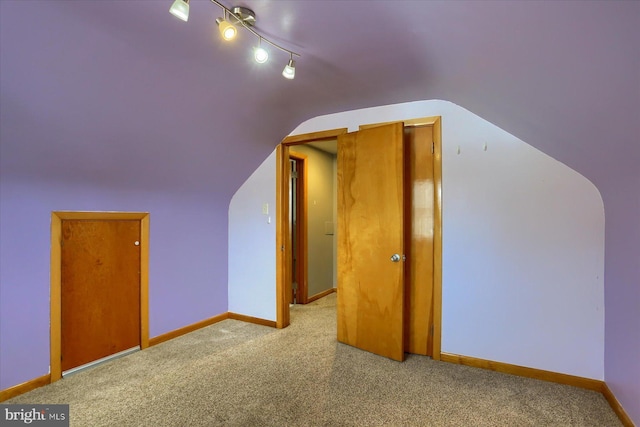 additional living space with light colored carpet and vaulted ceiling