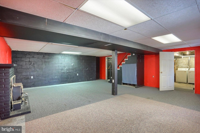 basement featuring a paneled ceiling, carpet flooring, and washer and dryer