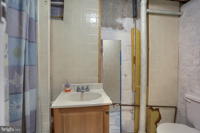 bathroom featuring vanity, tile walls, and toilet