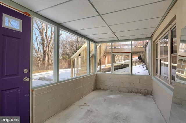 unfurnished sunroom with a healthy amount of sunlight and a drop ceiling