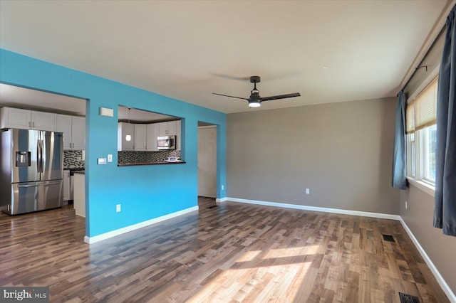 unfurnished living room featuring dark wood-type flooring and ceiling fan