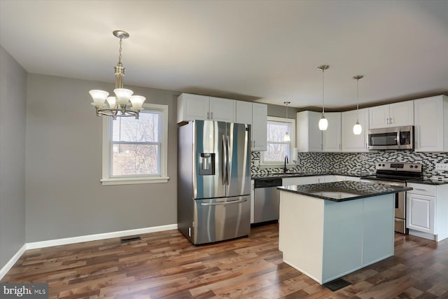 kitchen featuring white cabinetry, appliances with stainless steel finishes, pendant lighting, and decorative backsplash