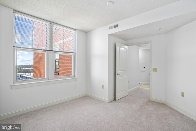 carpeted spare room with a textured ceiling