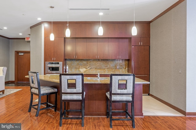 kitchen with paneled refrigerator, oven, light hardwood / wood-style floors, and decorative light fixtures