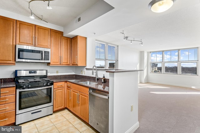 kitchen with sink, light tile patterned floors, a textured ceiling, and appliances with stainless steel finishes