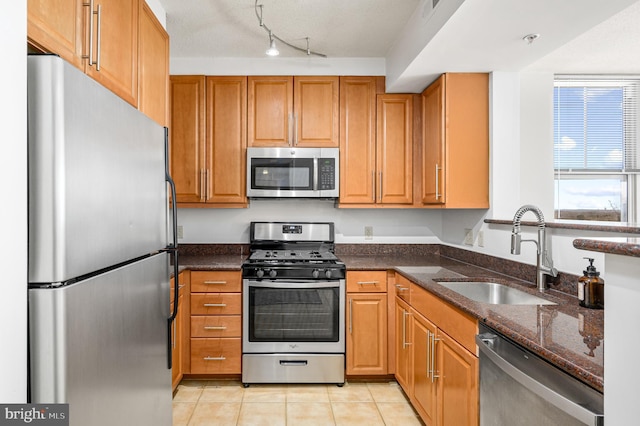 kitchen with dark stone countertops, appliances with stainless steel finishes, sink, and light tile patterned floors