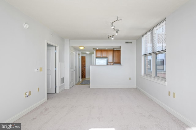 unfurnished living room featuring light colored carpet and track lighting