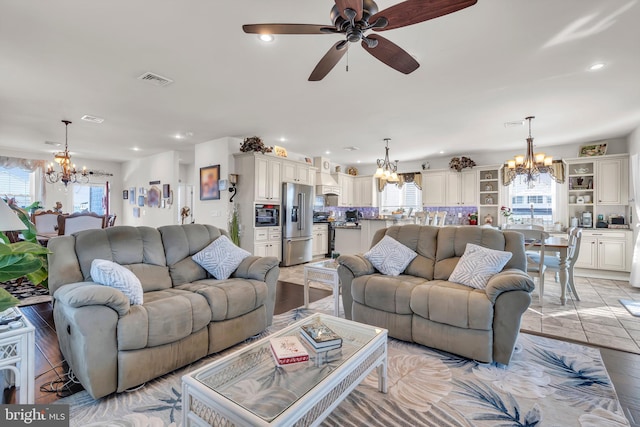 living room featuring ceiling fan with notable chandelier and light hardwood / wood-style flooring