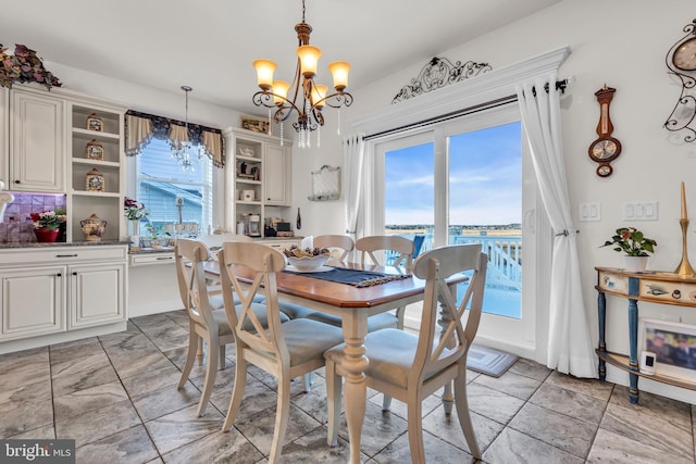 dining area with a water view, plenty of natural light, and an inviting chandelier