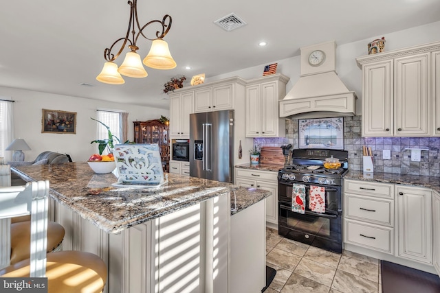 kitchen featuring pendant lighting, high quality fridge, custom exhaust hood, dark stone counters, and range with two ovens