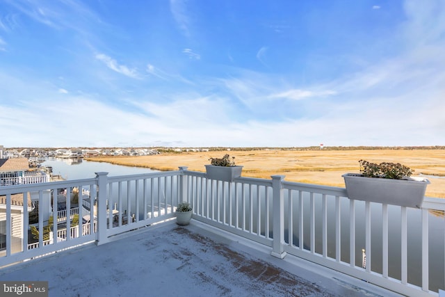 view of patio / terrace featuring a rural view, a balcony, and a water view