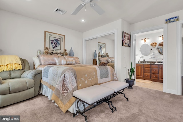 bedroom with light colored carpet, a closet, ceiling fan, and ensuite bathroom