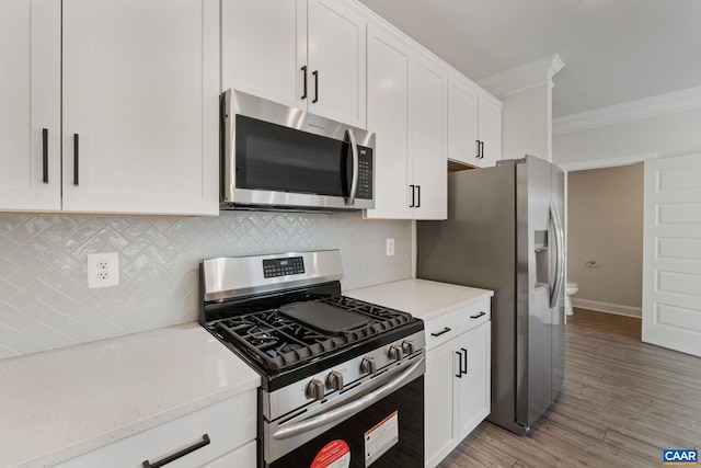 kitchen featuring white cabinetry, crown molding, light stone counters, tasteful backsplash, and appliances with stainless steel finishes