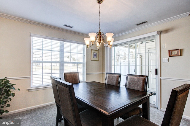 dining room with crown molding, carpet flooring, and a chandelier