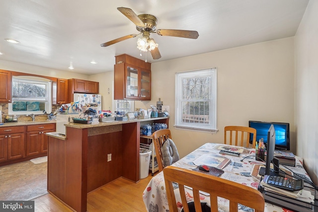 kitchen featuring backsplash, white fridge, ceiling fan, kitchen peninsula, and light wood-type flooring