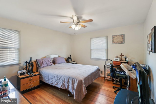 bedroom with hardwood / wood-style flooring, ceiling fan, and multiple windows