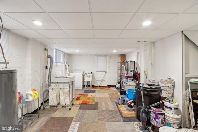 basement featuring water heater, sink, a paneled ceiling, and washer and clothes dryer