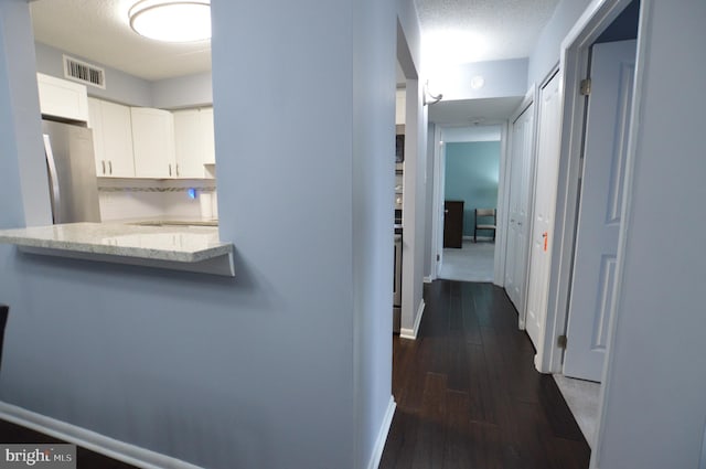 hallway with dark hardwood / wood-style floors and a textured ceiling