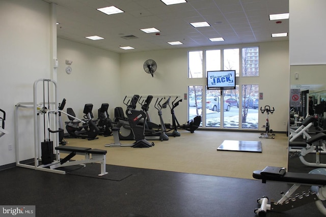 gym featuring a towering ceiling and a drop ceiling