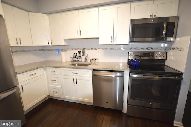 kitchen with sink, appliances with stainless steel finishes, white cabinetry, dark hardwood / wood-style floors, and light stone countertops