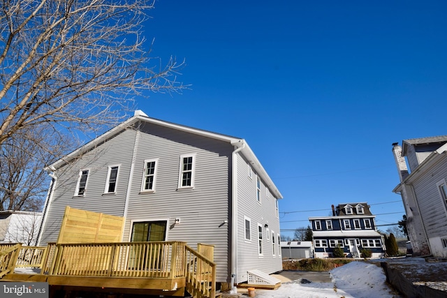 snow covered rear of property with a wooden deck