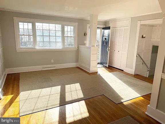 empty room with ornate columns, crown molding, plenty of natural light, and hardwood / wood-style floors