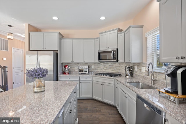 kitchen featuring appliances with stainless steel finishes, light stone countertops, sink, and decorative backsplash